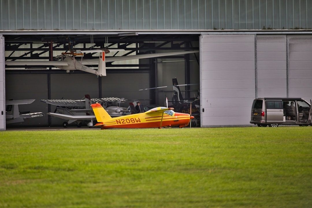 Kleine Flugzeuge vor einem Hangar auf einer grasbewachsenen Flugplatzfläche
