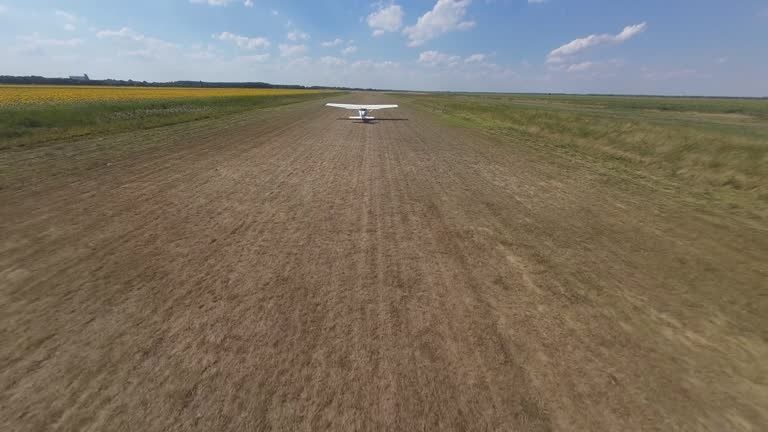Kleines Flugzeug auf einer unbefestigten Graspiste zwischen Feldern